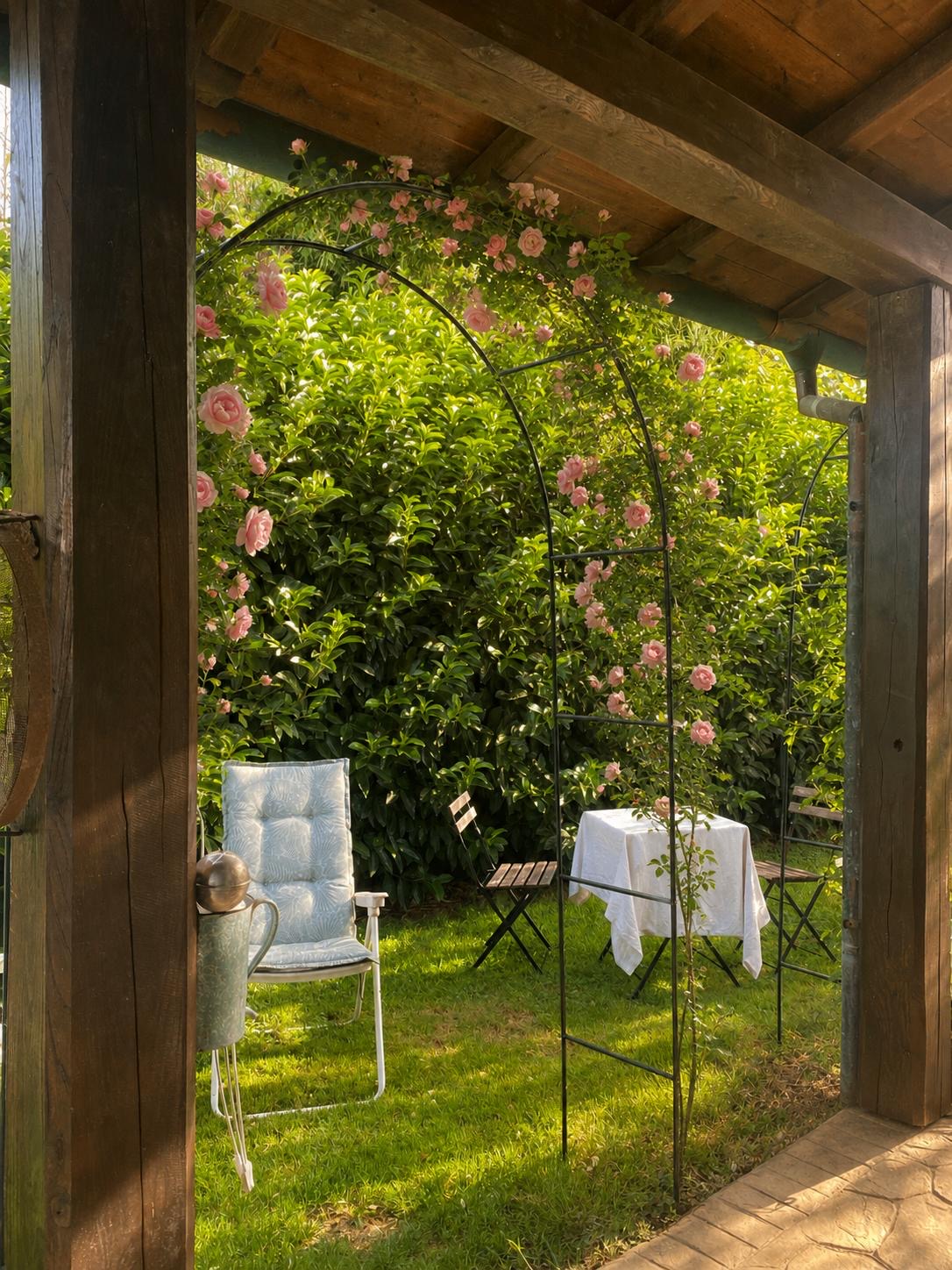 Pergolato in legno con arco di rose e tavolino nel giardino