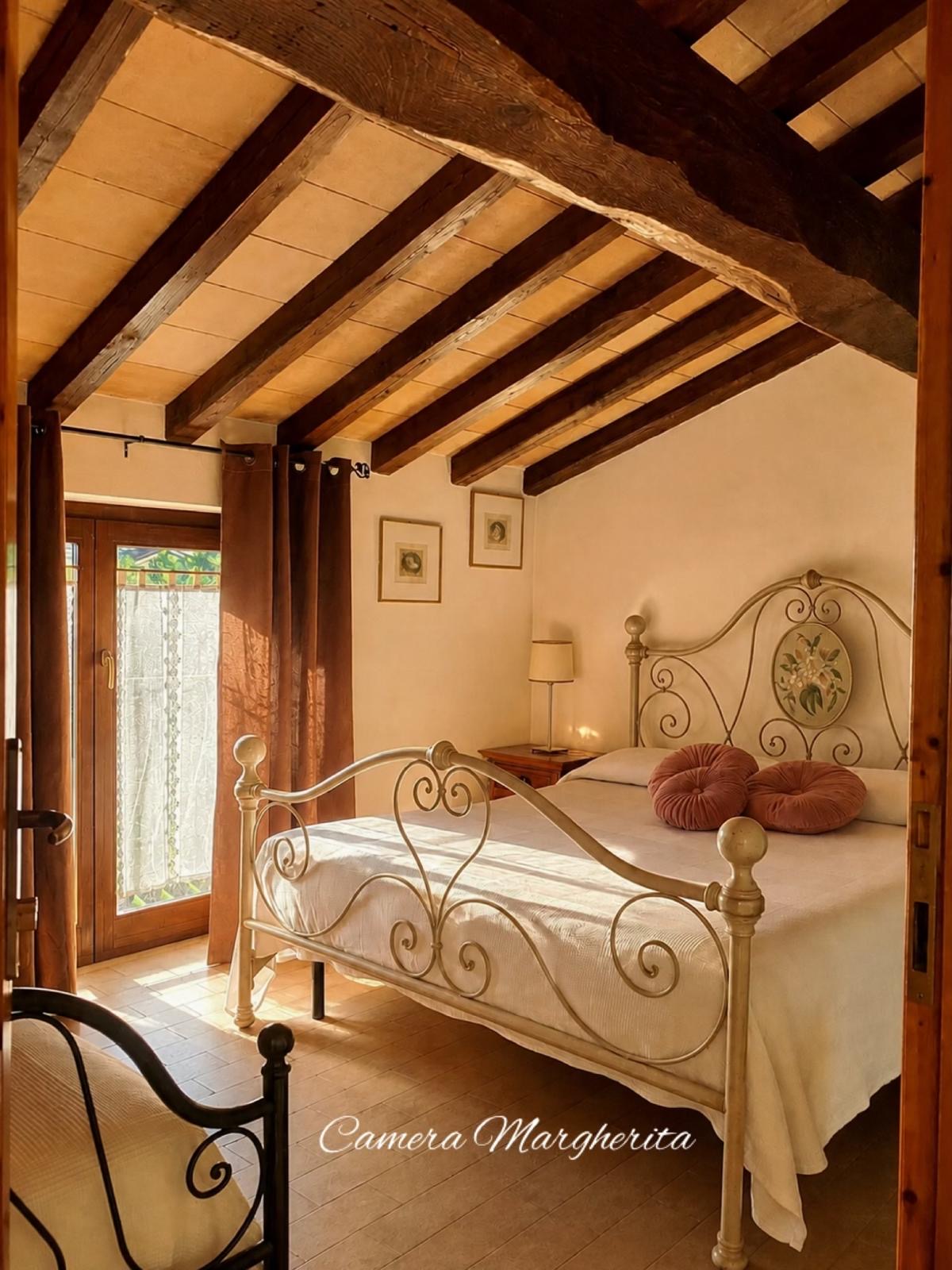 Camera Margherita con letto in ferro battuto e travi in legno a vista